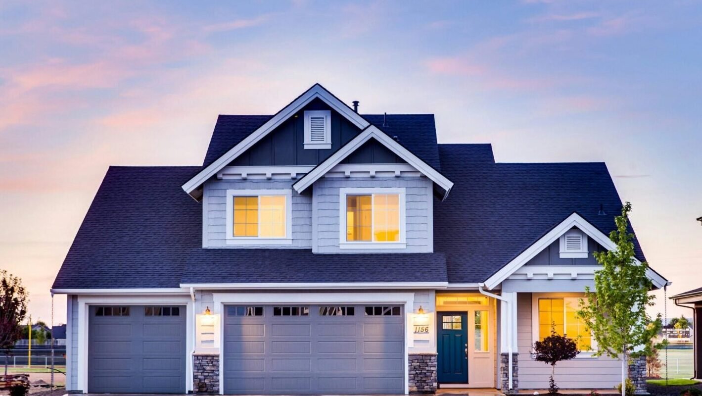 Beautiful two-story house with illuminated windows and garage at dusk.