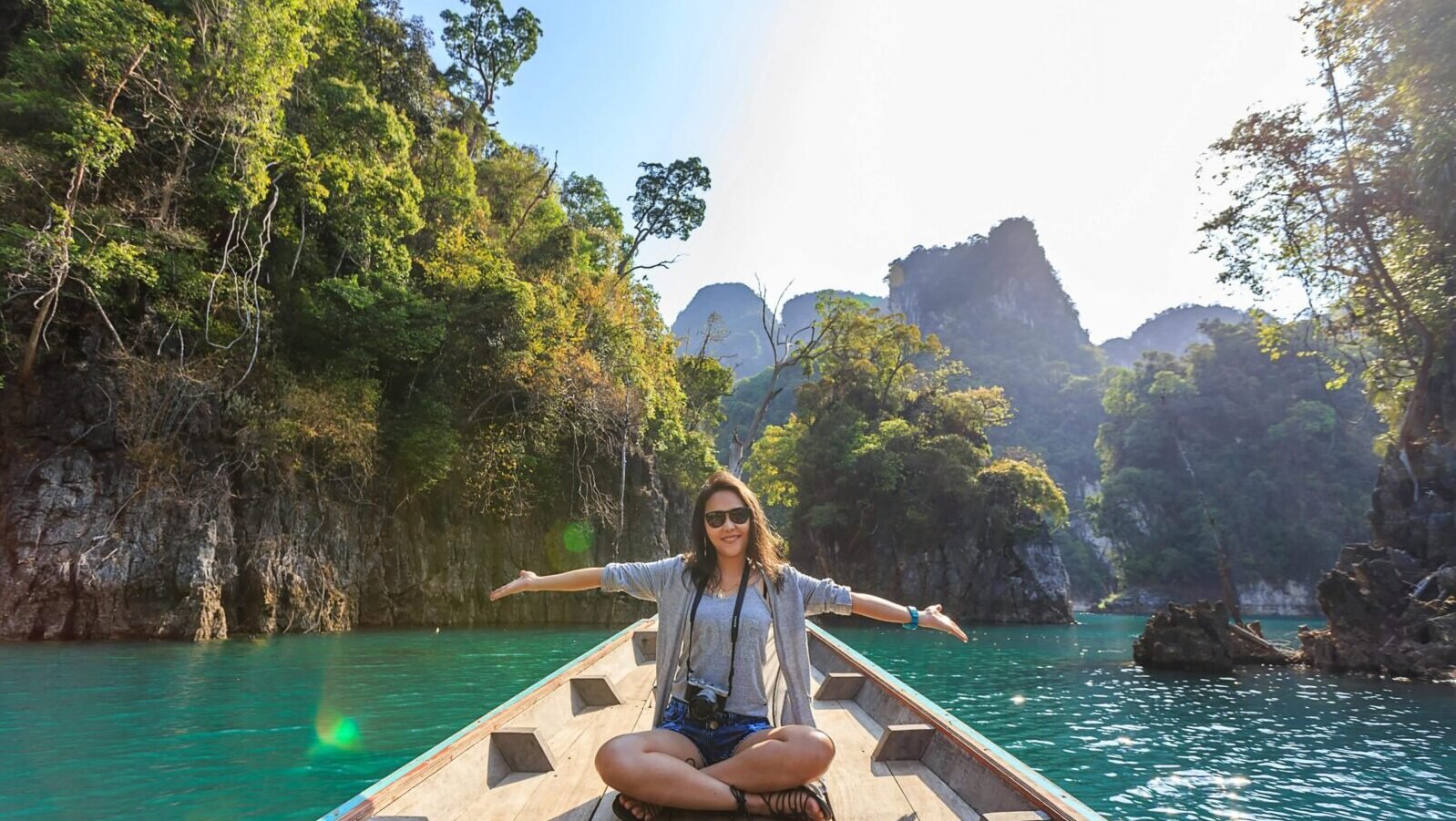 Asian woman relishing a serene boat journey through the lush karst landscape of Thailand's Khlong Sok.