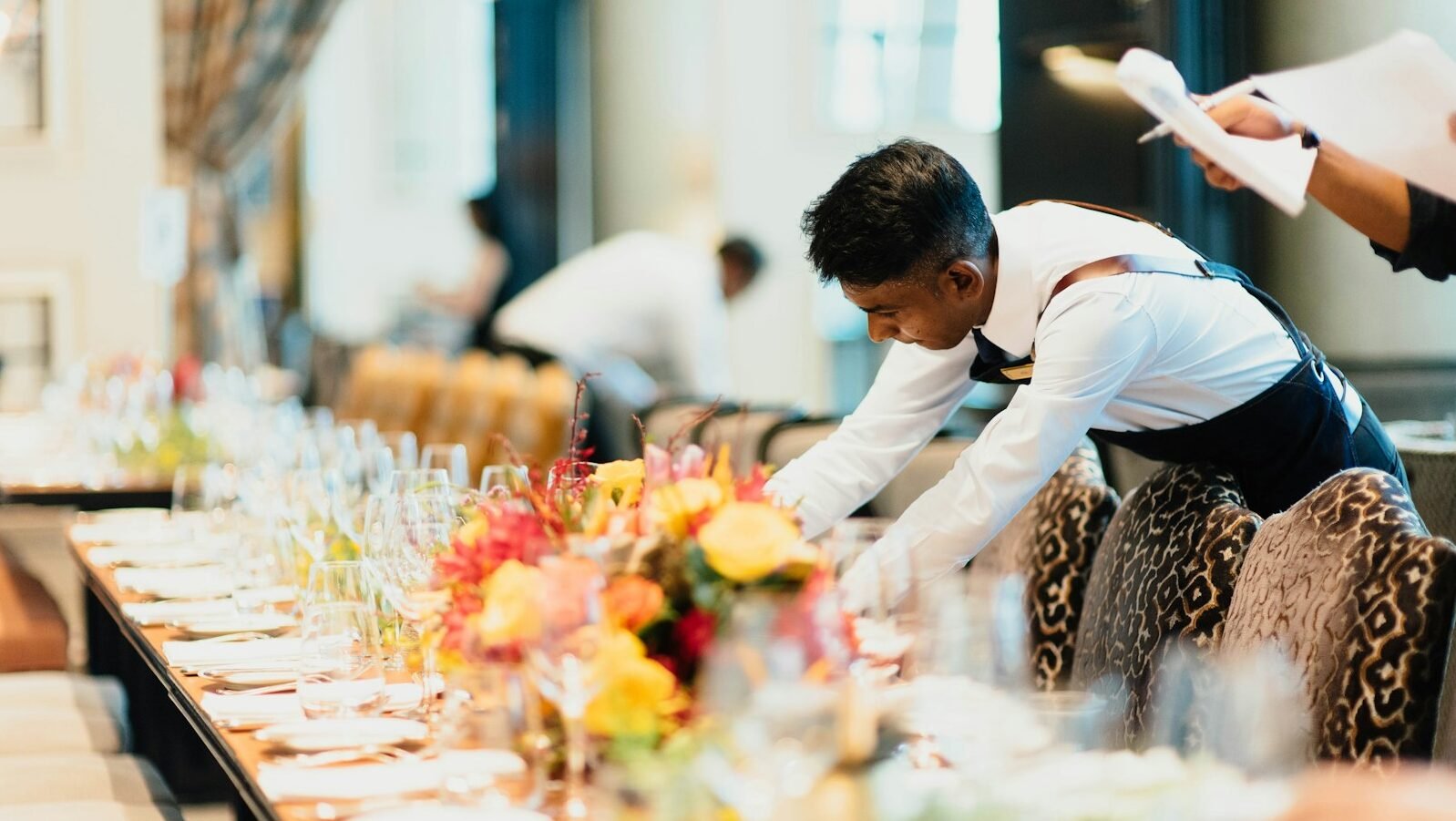 man in white top standing next to table
