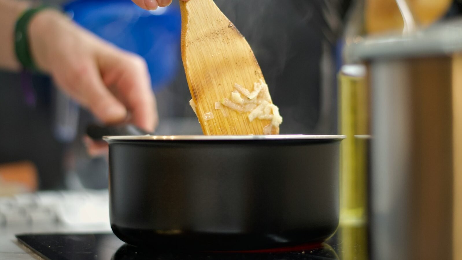 a person stirring a pot with a wooden spoon